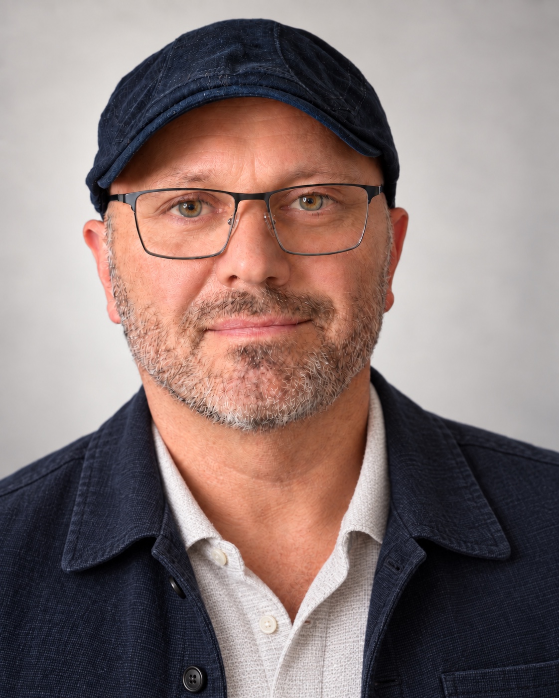 Max Theodor facing the camera, wearing glasses and a navy cap